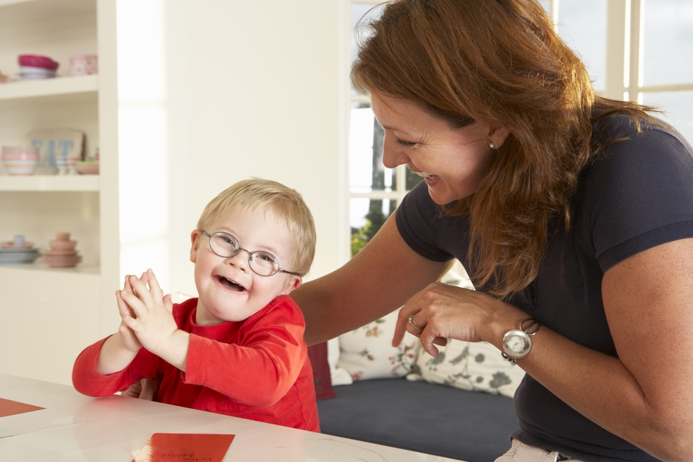 a woman playing with a young child who wears glasses