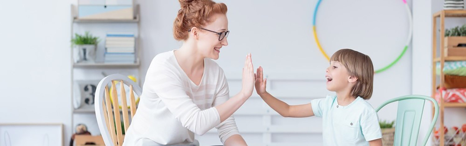 A woman and a young child sitting on chairs and high fiving each other
